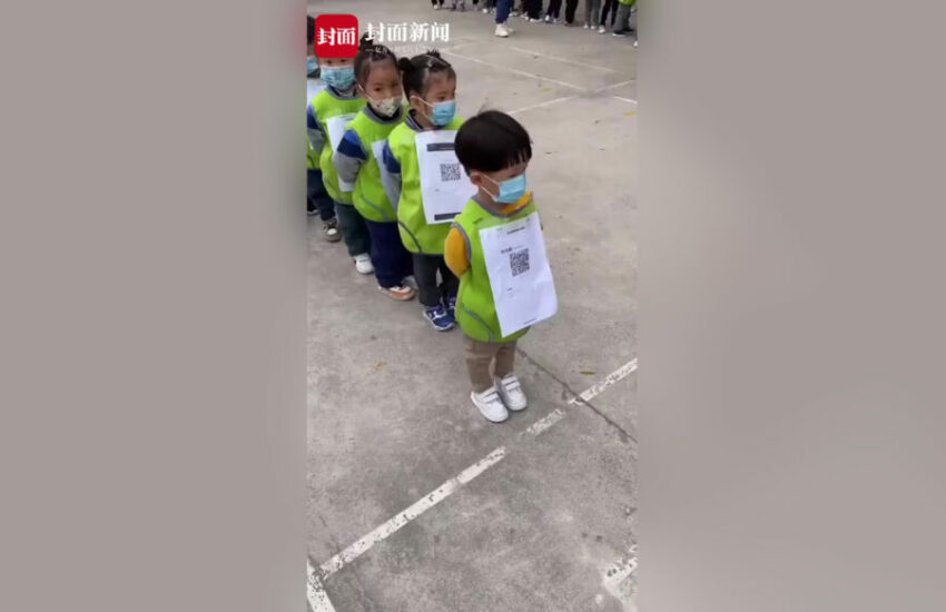 Cina: Bambini di un asilo in una lunga fila ordinata con un QR CODE sul petto